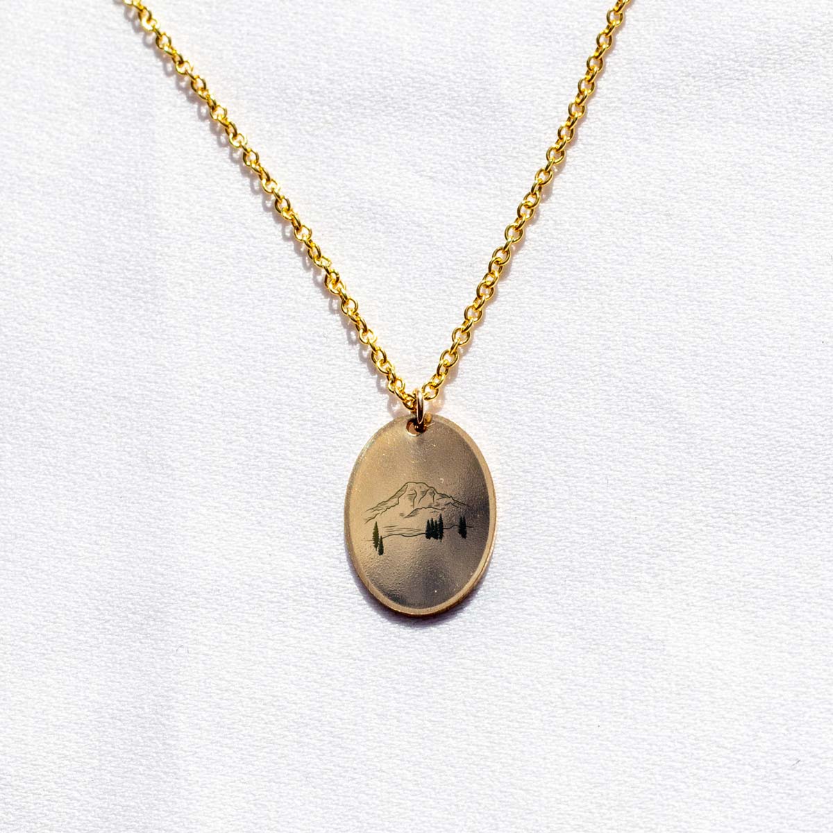 Gold fill oval charm with an engraving of a mountain peak