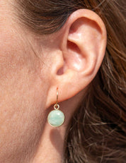 Close-up of an ear wearing a 14k gold fill dangle earring set with greenish blue Amazonite