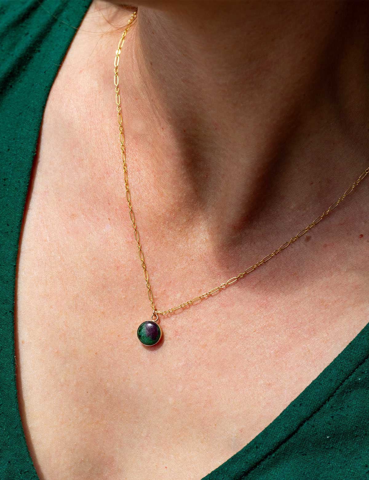 Gold fill necklace with a green natural stone pendant on a person wearing a green top.