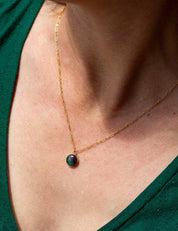 Gold fill necklace with a green natural stone pendant on a person wearing a green top.