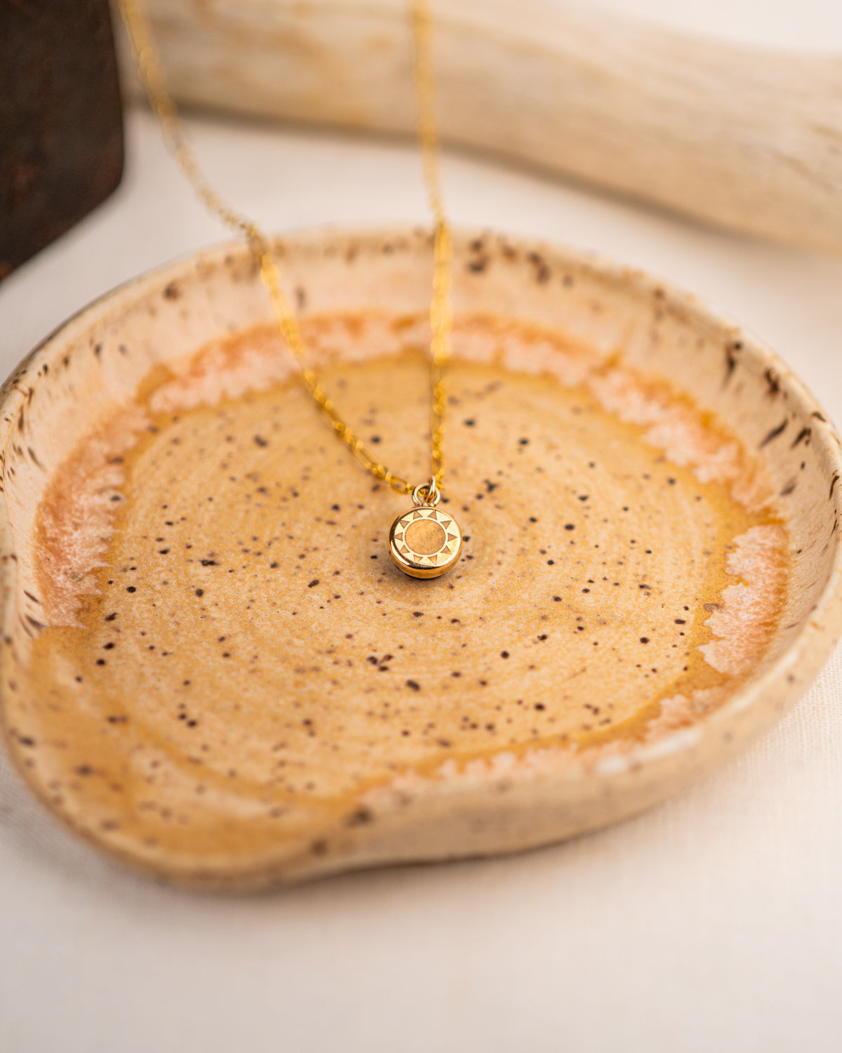 Gold necklace with a pendant engraved with a sun