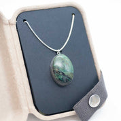 Natural green stone set as an oval pendant, packaged in a kraft gift box