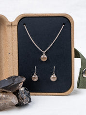 Custom jewelry set with necklace and earrings made from the same gray crystal, displayed in an open kraft jewelry box