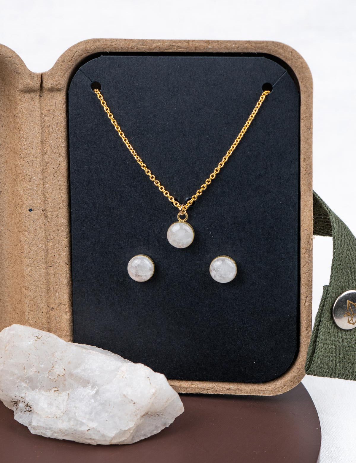 Mini jewelry set with necklace and stud earrings in a kraft gift box, next to the original natural rock they were made from