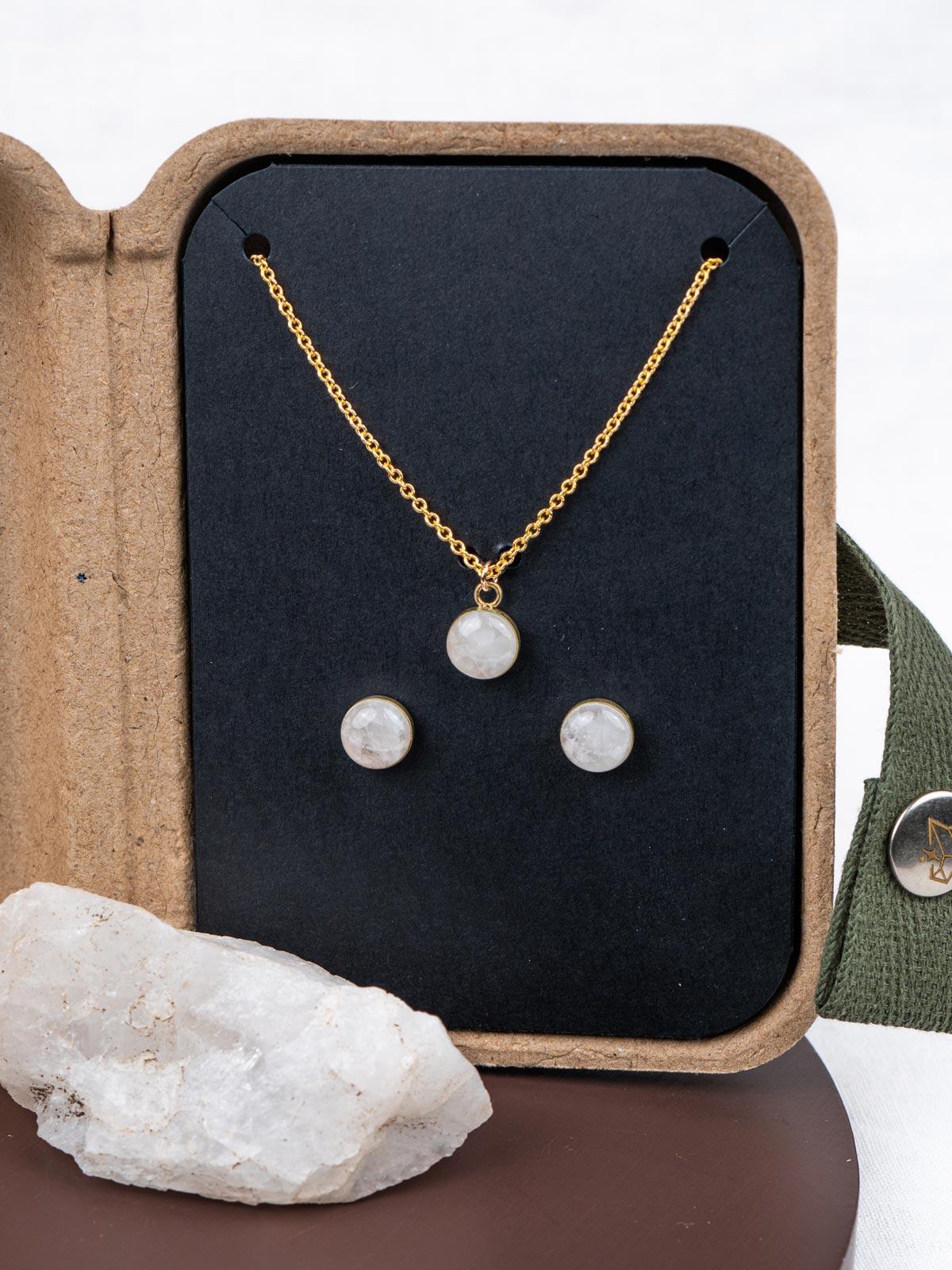 Mini jewelry set with necklace and stud earrings in a kraft gift box, next to the original natural rock they were made from