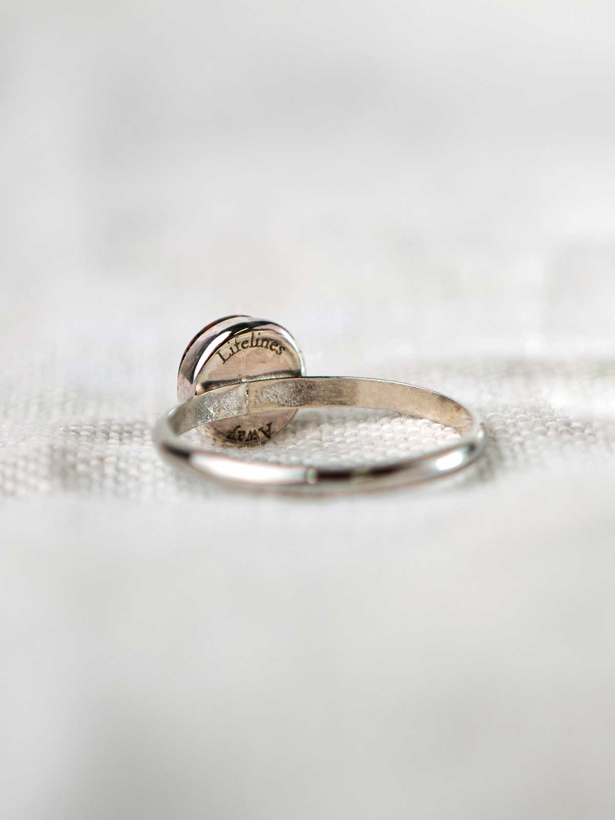 Sterling silver ring with a round stone engraved on the back