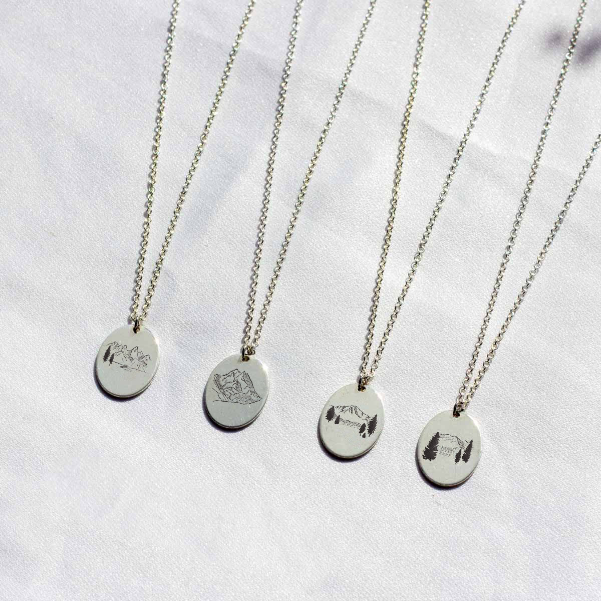 four voyager charm necklaces with mountain peak designs.  Grand tetons,  Denali, Pikes Peak, and Mount Mitchell charms pictured