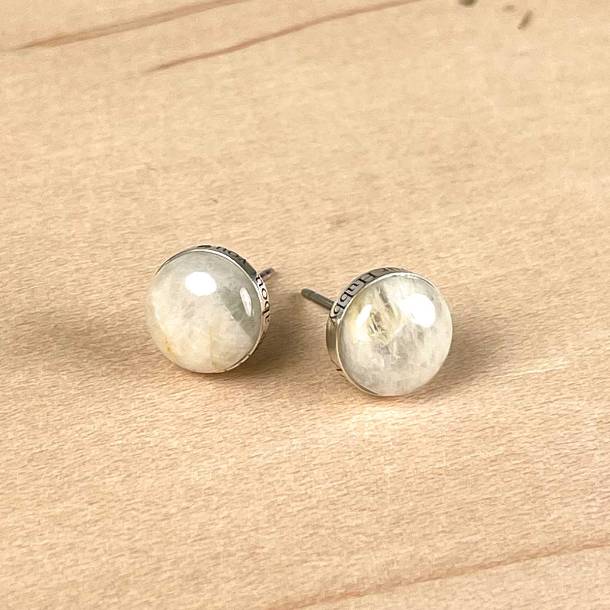 Pair of round sterling silver stud earrings set with a natural stone and custom engraved on the edge