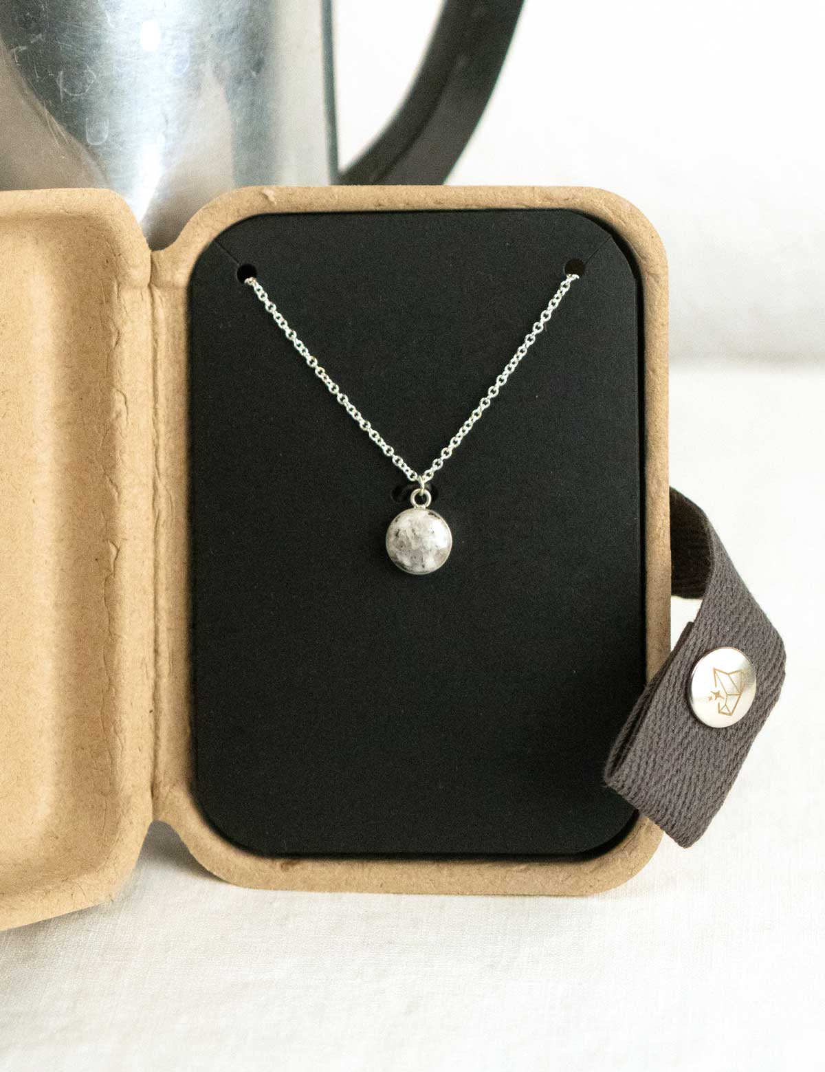 Sterling silver necklace with a natural granite stone pendant in an open kraft jewelry box