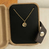 Gold necklace with a crystal pendant on a cable chain in an open jewelry box 