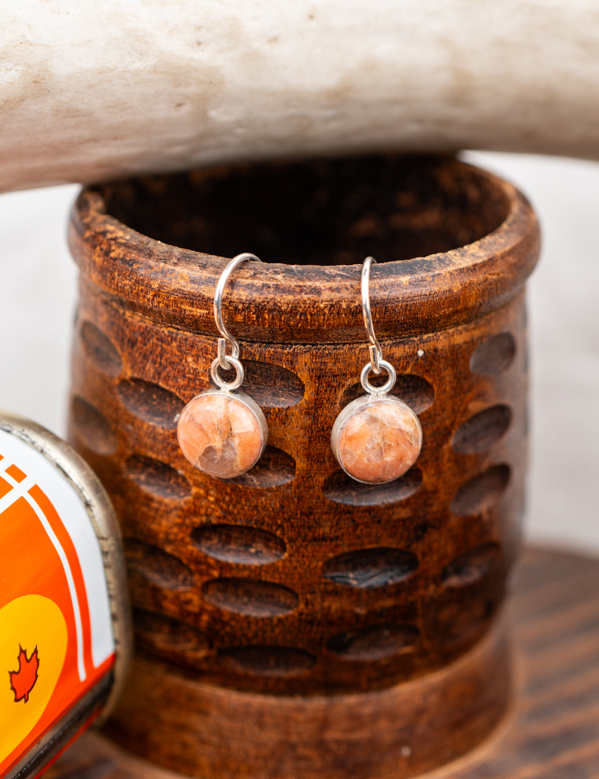 Pair of earrings with round pink stones in a wooden holder.
