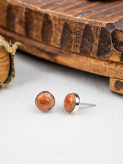 Pink Granite earrings with silver posts on a white surface with a wooden box in the background.