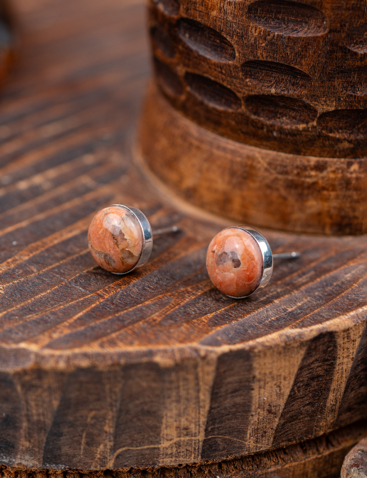 Pair of round earrings with a natural stone design on a wooden surface