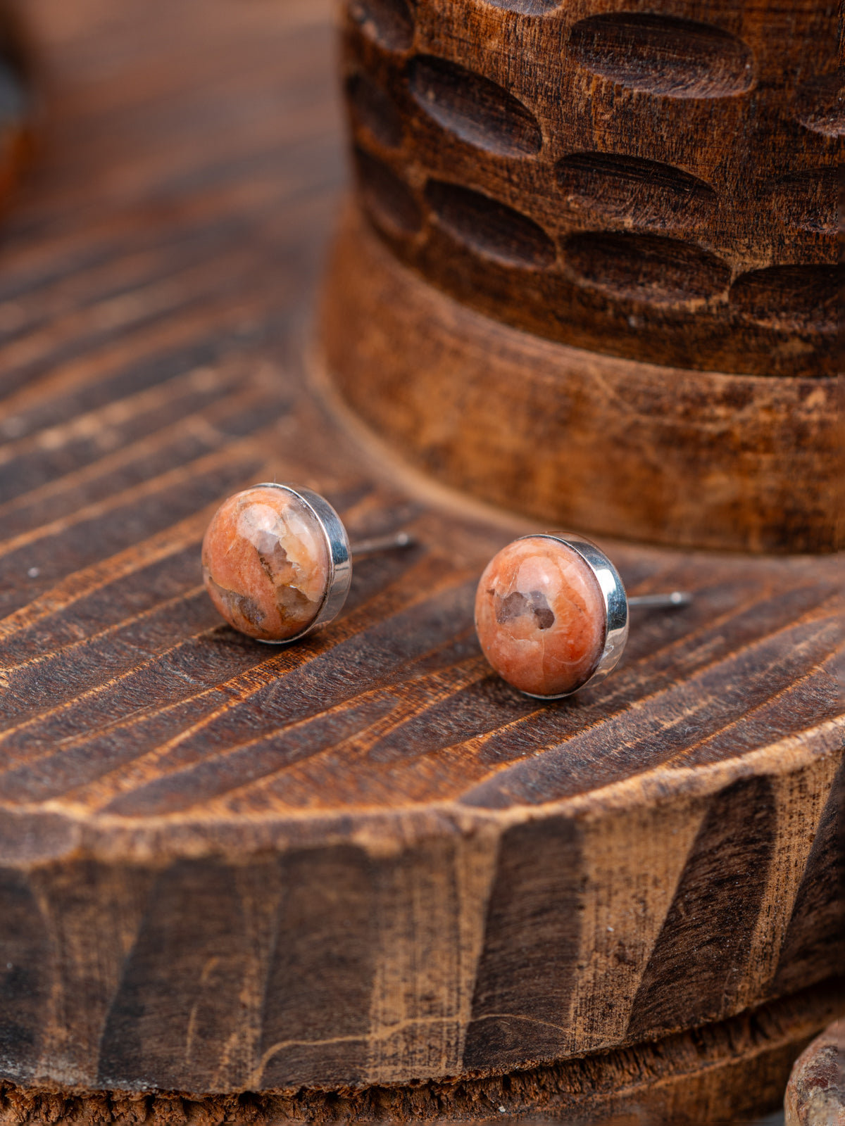 Pair of round earrings with a natural stone design on a wooden surface