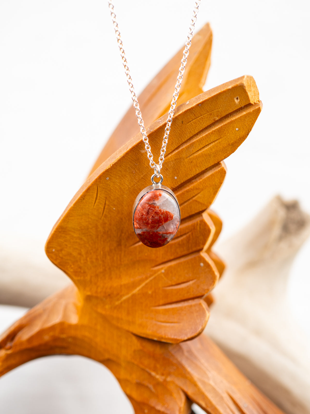 Necklace with a red stone pendant on a wooden stand
