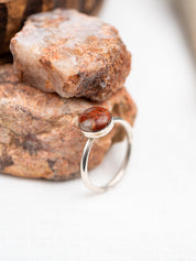 Silver ring with a pink granite on a rock background