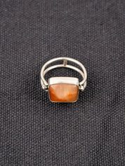 Silver ring with a double band design featuring a soft pink opal stone, displayed on a dark fabric background.