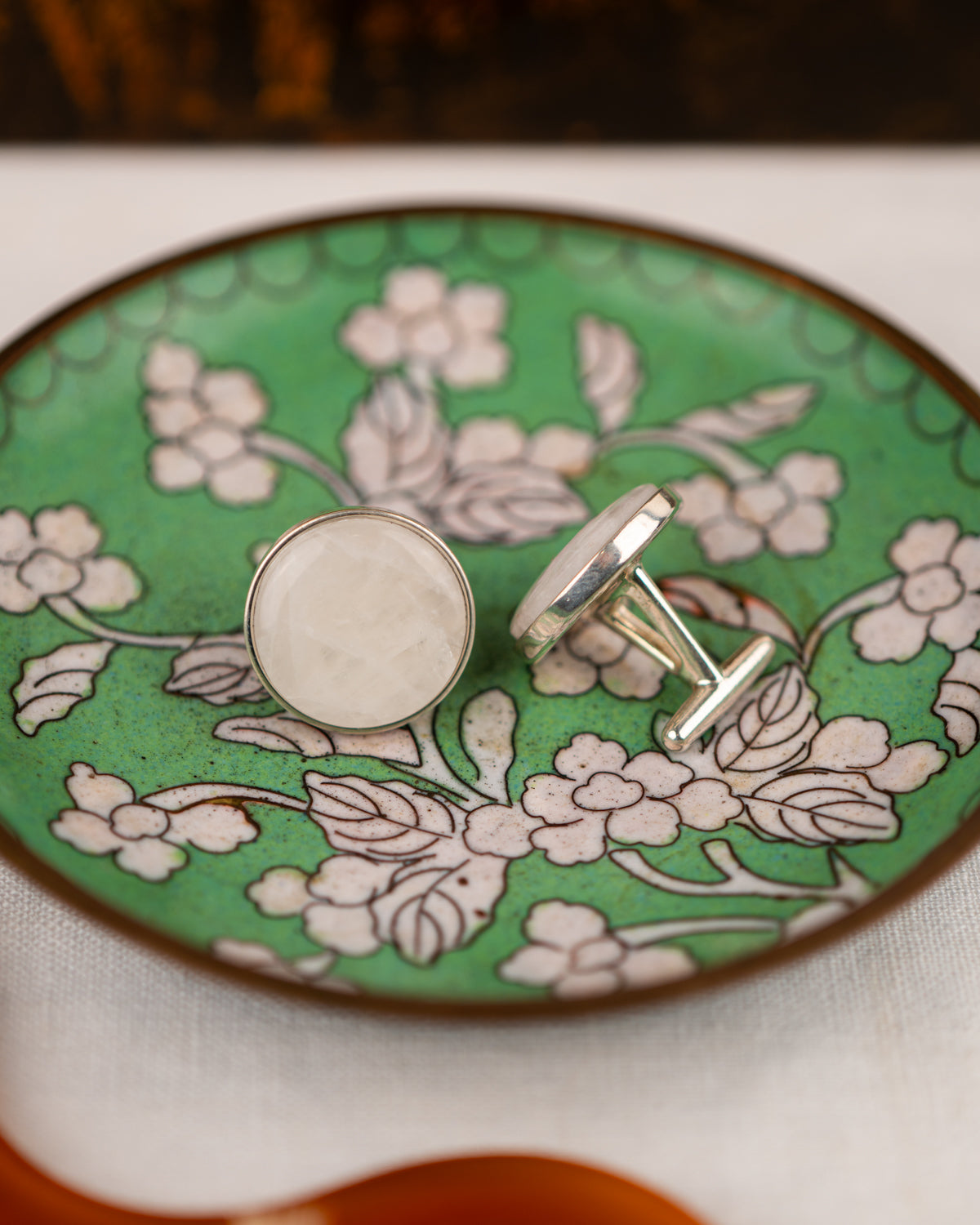 White colored milky quartz set into a sterling silver cufflinks on a green bowl