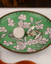 White colored milky quartz set into a sterling silver cufflinks on a green bowl
