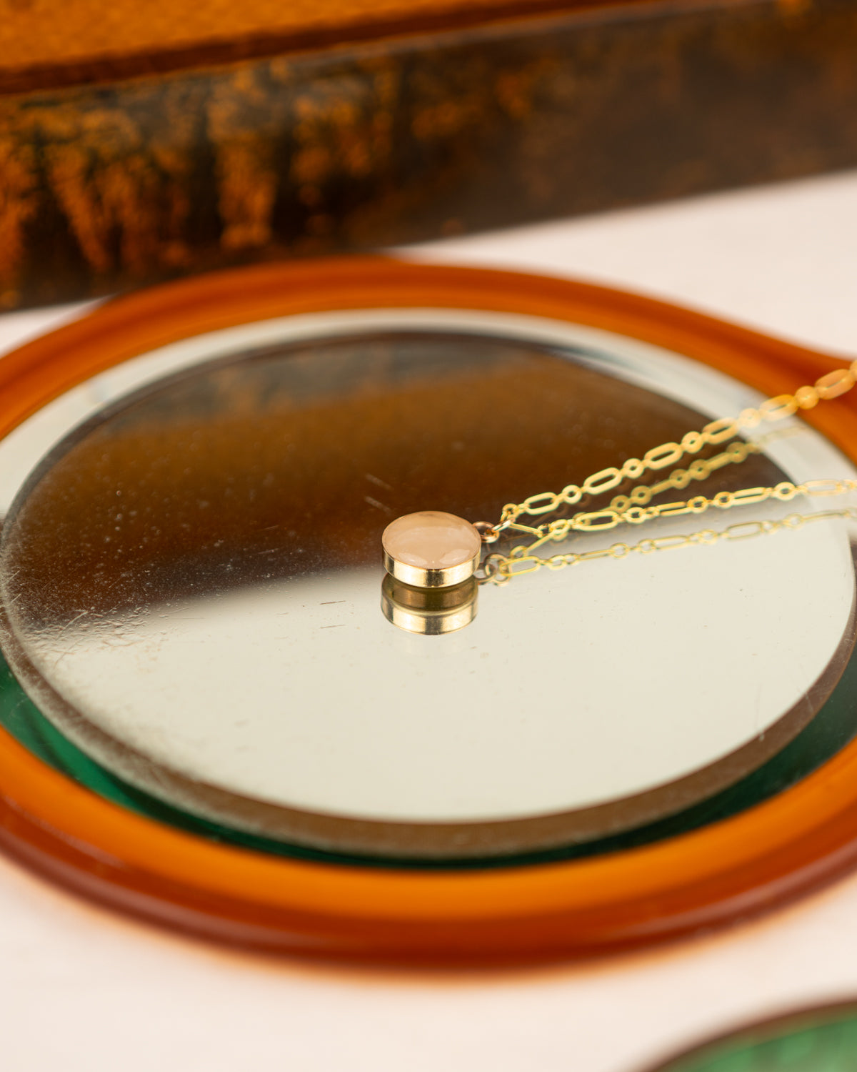 White colored milky quartz set into 14K Gold Fill pendant on a mirror