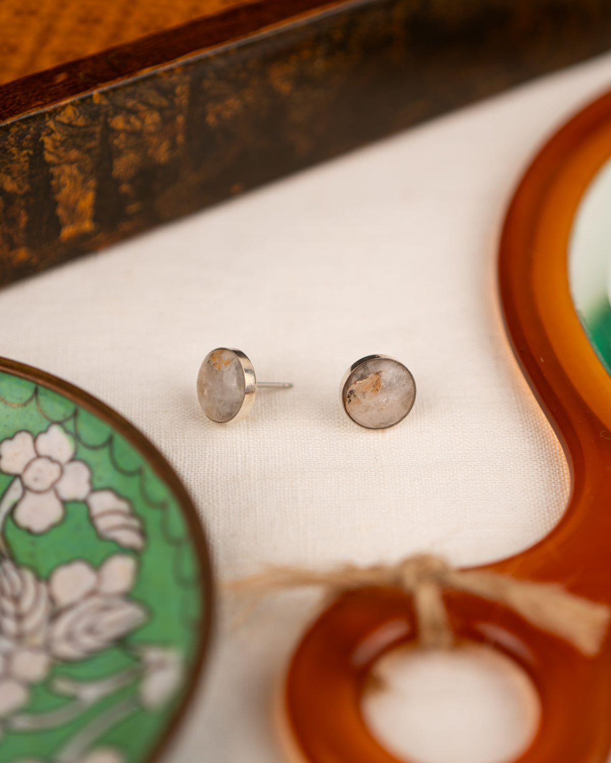White colored milky quartz earrings amid props on a white linen