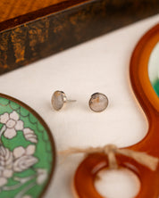 White colored milky quartz earrings amid props on a white linen