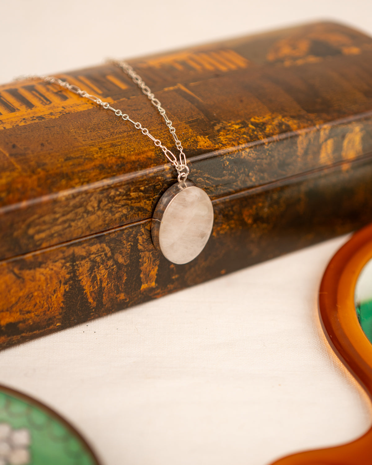 White colored milky quartz set into a sterling silver pendant draped over a box