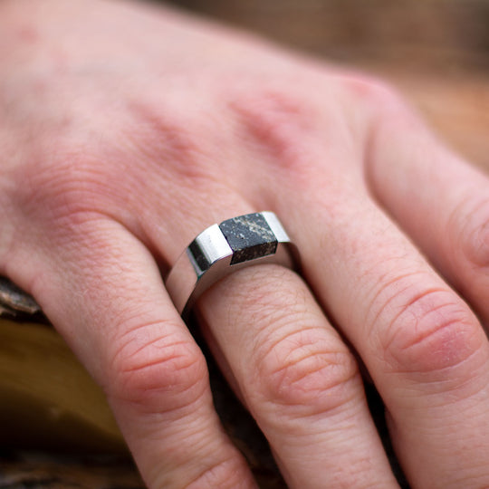 A man wears a large stainless steel signet ring set with a natural granite stone