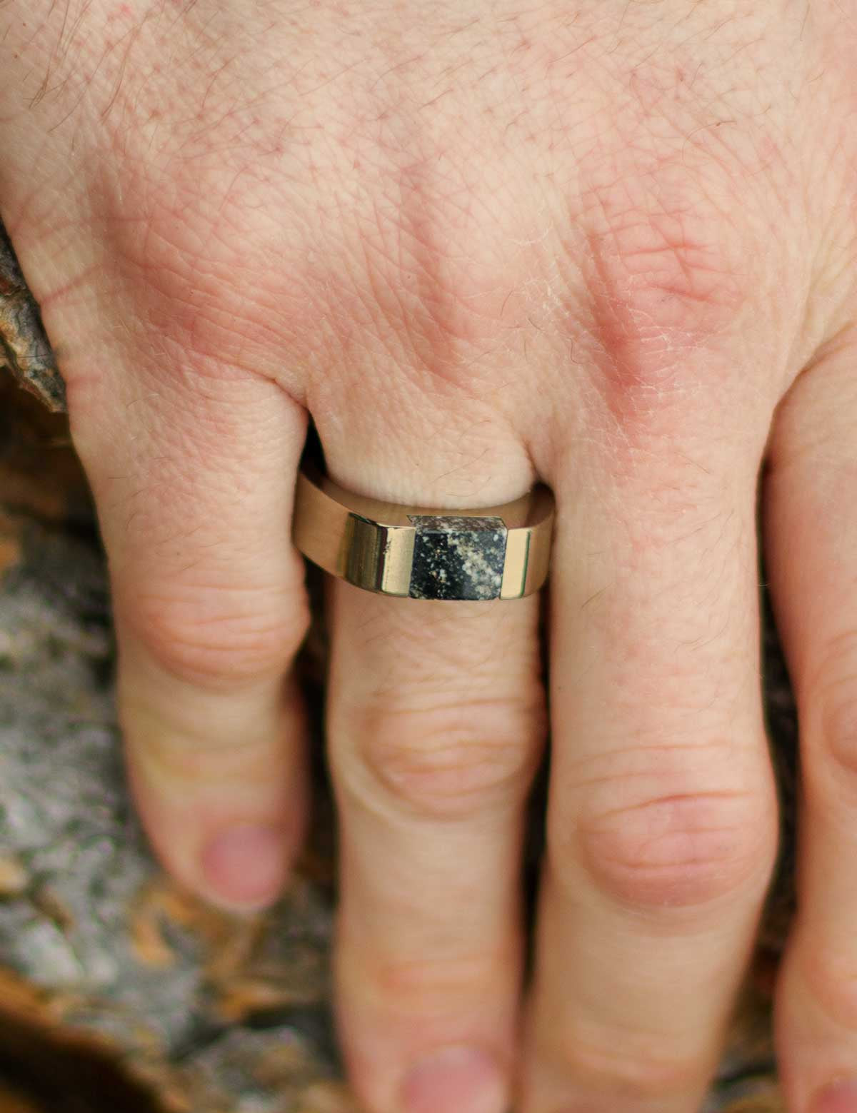 Champagne color stainless steel signet ring with black granite stone inlay on a man's finger