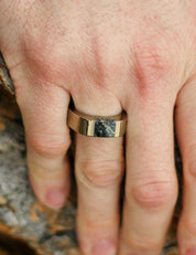 Champagne color stainless steel signet ring with black granite stone inlay on a man's finger