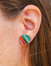 Close-up of an ear wearing a colorful round statement earring.