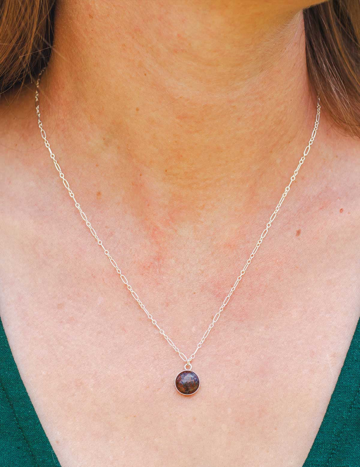 Dainty stone pendant necklace made from a natural rock worn by a woman, close-up view