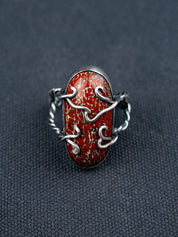 Dinosaur bone stone ring featuring a patterned fossilized gemstone set in a metal bezel with a twisted band, displayed on dark textured fabric.