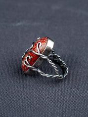 Side profile of a Dinosaur bone stone ring featuring a patterned fossilized gemstone set in a metal bezel with a twisted band, displayed on dark textured fabric.