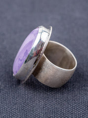 Sterling silver ring featuring a Tiffany stone with natural purple tones, photographed from the side on a gray background