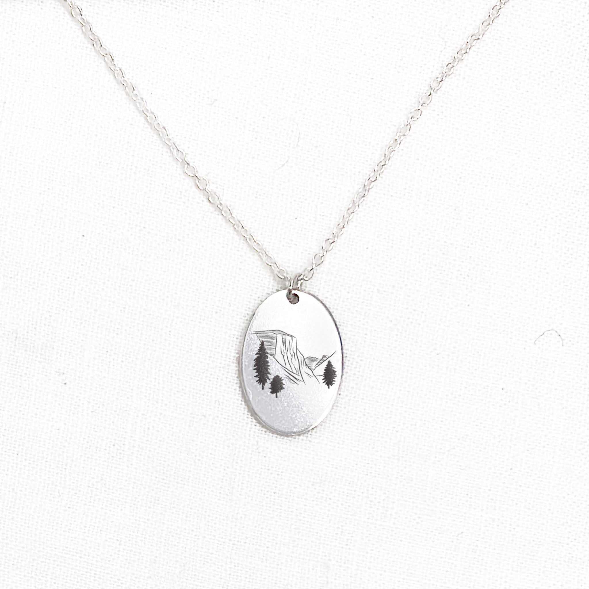 a voyager charm necklace with a mountain engraving