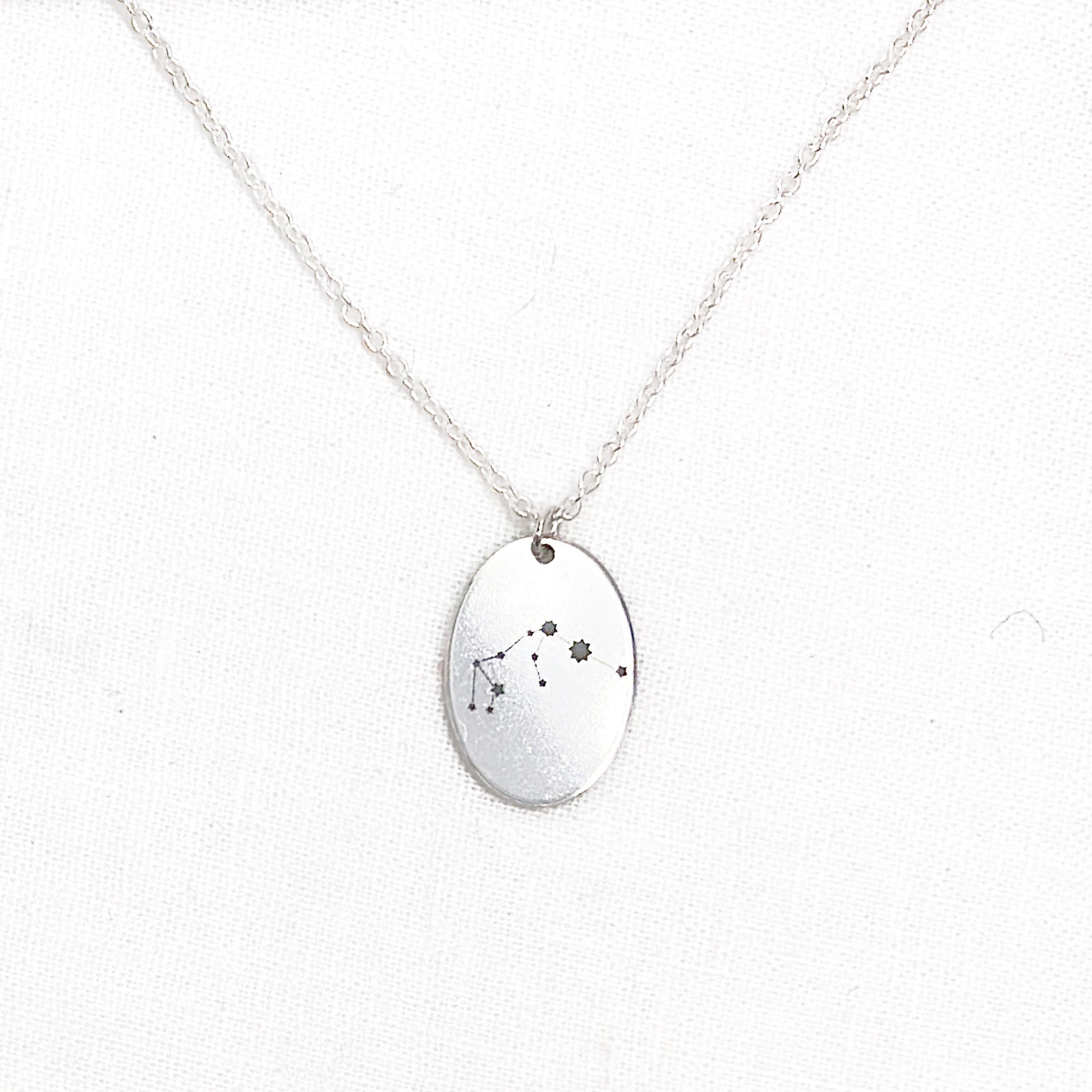 a voyager charm necklace with a zodiac constellation engraving