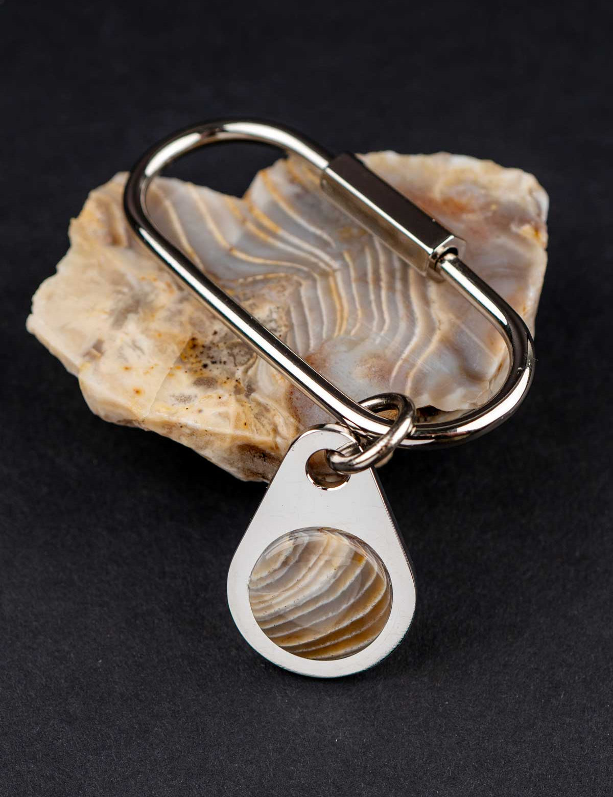 Keychain with a teardrop-shaped tag featuring an agate stone, placed on the customer's rock it was made from