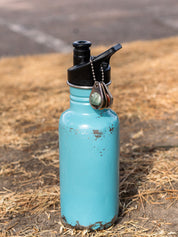 Blue water bottle sitting outside with a set of 3 custom zipper pull tags adorned with round stones and personalized engraving