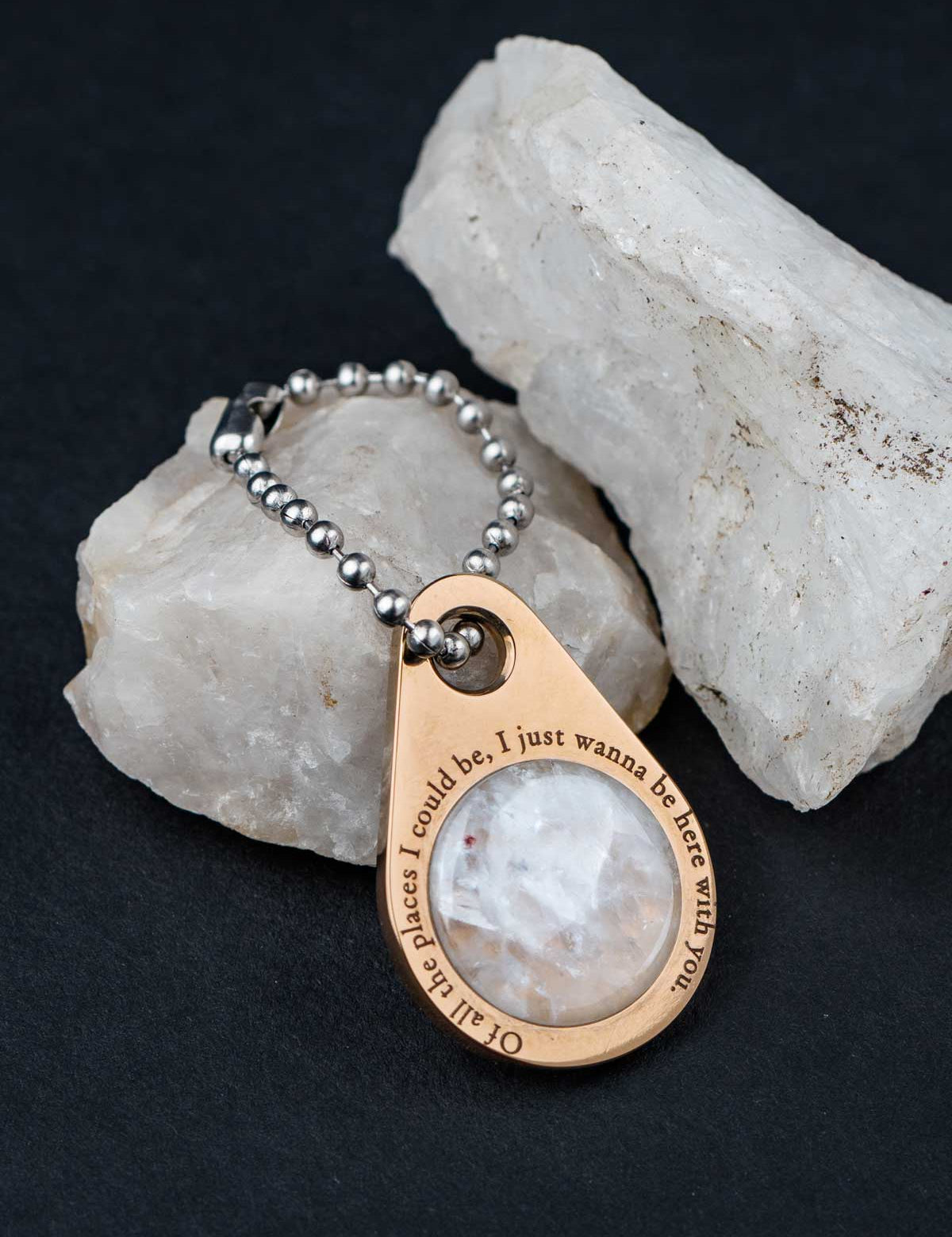 Custom zipper pull on a ball chain set with white quartz sitting on the rock it was made from