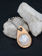 Custom zipper pull on a ball chain set with white quartz sitting on the rock it was made from