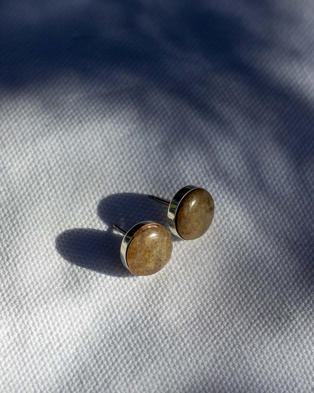 Pair of green stone stud earrings with a sterling silver setting