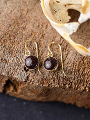 Dangling red fossilized dinosaur gembone earrings with a gold ear wire and backing