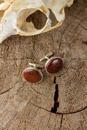 Red fossilized dinosaur bone set as round cufflinks with a whale tail back