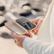 A man holds an open kraft gift box that holds a set of beautiful blue-green stone cufflinks