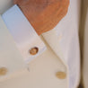 A man in a white suit wears a custom natural stone cufflink made of brown rock