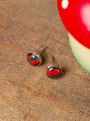 Colorful round surfite stud earrings on a wooden surface