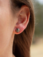 Close-up of an ear wearing a small round stone stud earring