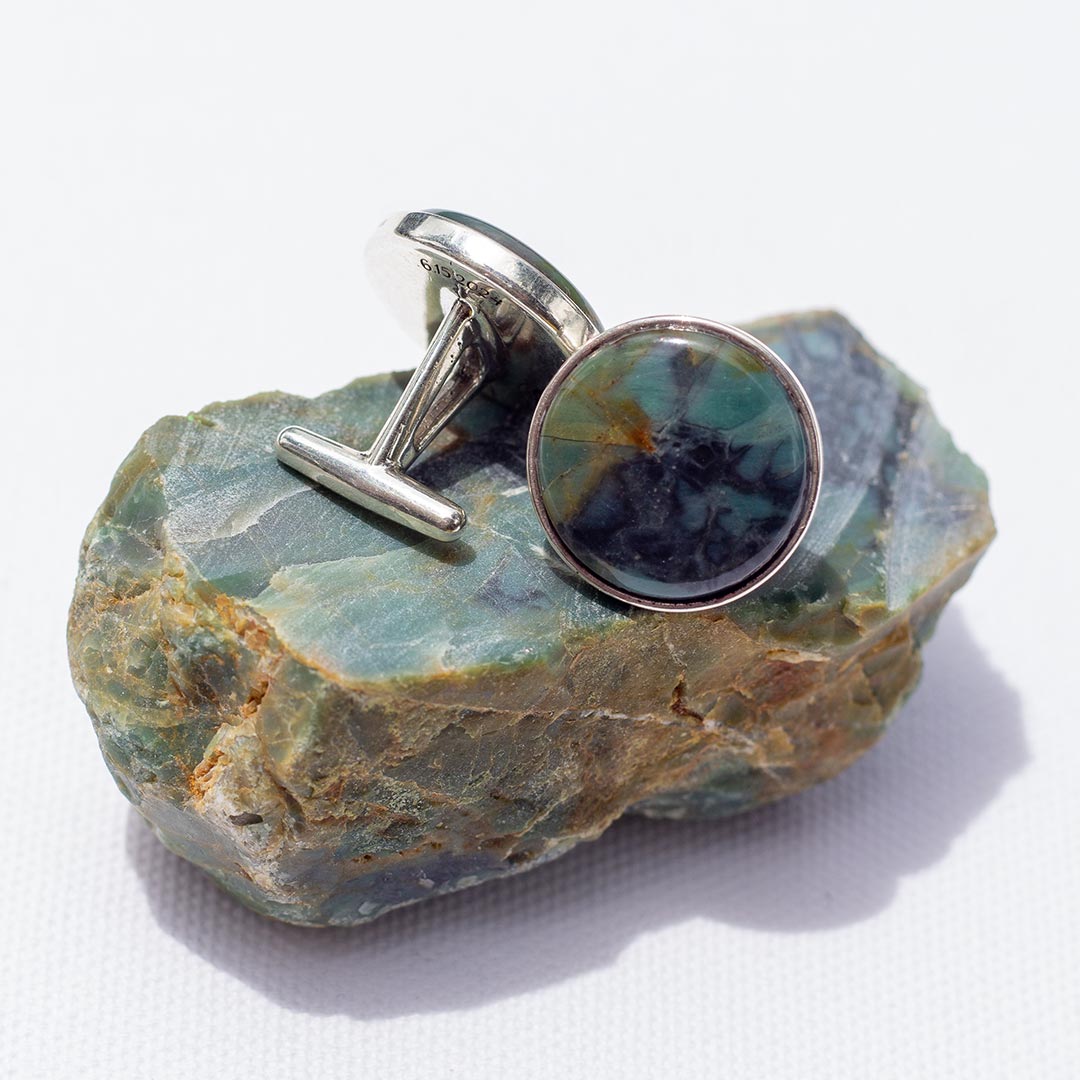 A set of blue-green cufflinks set in sterling silver sit on top of the fist-sized they were made from