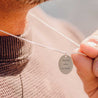 Man holding a charm necklace engraved with names and a date